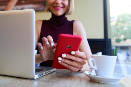Zbliżone zdjęcie białej kobiety używającej smartfonu do pracy na odległość w kawiarni