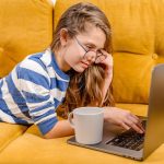Uśmiechnięta nastolatka z Europy używa laptopa do wideorozmów z przyjaciółmi i rodzicami