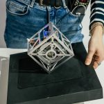 Częściowo zamazana metalowa kostka elektroniczna, która pozostaje w równowadze po umieszczeniu na jednej krawędzi