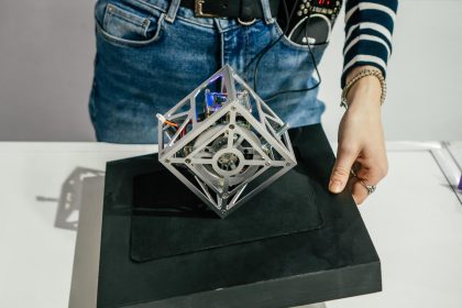 Częściowo zamazana metalowa kostka elektroniczna, która pozostaje w równowadze po umieszczeniu na jednej krawędzi