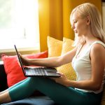 Portret atrakcyjna młoda blondynka bizneswoman nosząca domowe ubrania, pracująca na laptopie w domu, siedząca na wygodnej kanapie w nowoczesnym mieszkaniu. Freelancer, studia, koncepcja pracy zdalnej.