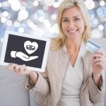 Kobieta trzyma tablet ręką dając pieniądze z sercem na cele charytatywne