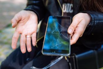 Telefon z pękniętym ekranem w dłoni sprawa nieobjęta gwarancją