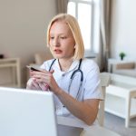 Atrakcyjna lekarka, która podczas konsultacji wyjaśnia leczenie pacjentowi poprzez wideorozmowę z laptopem