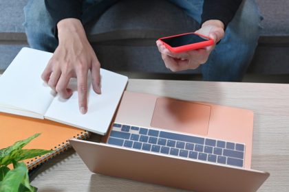 Mężczyzna trzymający smartfon i czytający informacje na notebooku