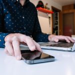 Zbliżenie na ręce człowieka za pomocą laptopa sprawdzającego smartfona
