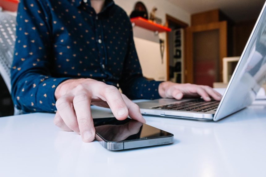 Zbliżenie na ręce człowieka za pomocą laptopa sprawdzającego smartfona