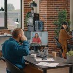 Przedsiębiorca używający słuchawek dousznych, aby porozmawiać z menedżerem podczas rozmowy wideo w biurze startowym. Biznes człowiek rozmawia z kobietą na zdalnej wideokonferencji online na komputerze, aby zaplanować projekt i strategię.