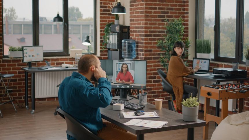 Przedsiębiorca używający słuchawek dousznych, aby porozmawiać z menedżerem podczas rozmowy wideo w biurze startowym. Biznes człowiek rozmawia z kobietą na zdalnej wideokonferencji online na komputerze, aby zaplanować projekt i strategię.