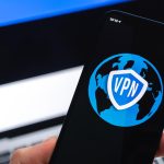 VPN w Estonii Koncepcja bezpiecznego i bezpiecznego internetu Prywatność Ręka z telefonem komórkowym i aplikacją VPN Flaga i laptop na zdjęciu w tle