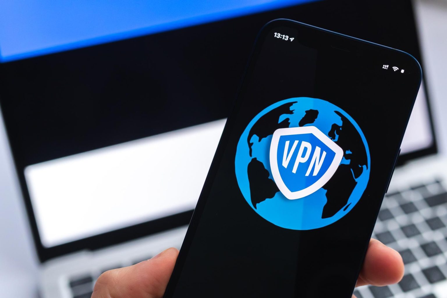 VPN w Estonii Koncepcja bezpiecznego i bezpiecznego internetu Prywatność Ręka z telefonem komórkowym i aplikacją VPN Flaga i laptop na zdjęciu w tle