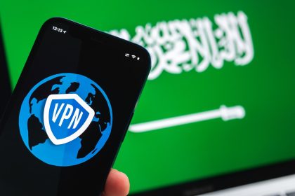 VPN w Arabii Saudyjskiej Bezpieczny i bezpieczny internet Prywatność Ręka z telefonem komórkowym i aplikacją VPN Flaga i laptop na zdjęciu w tle