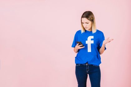 Kobieta używa telefon komórkowego wzrusza ramionami przeciw różowemu tłu