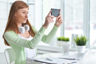 Portret młodej bizneswoman biorącej selfie w biurze