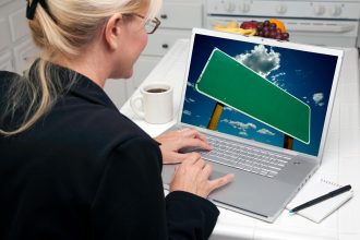 Kobieta w kuchni używająca laptopa z pustym znakiem drogowym na ekranie