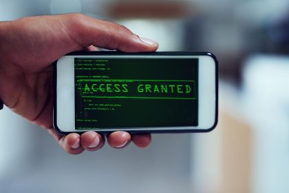 Nawet Twój smartfon nie jest bezpieczny Ujęcie niezidentyfikowanego mężczyzny, który używa smartfona do włamania się do sieci komputerowej
