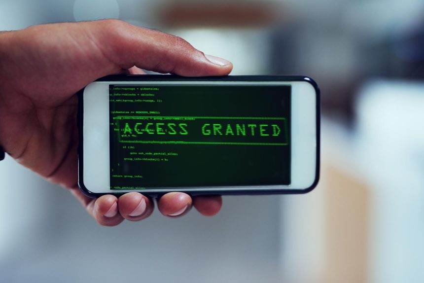 Nawet Twój smartfon nie jest bezpieczny Ujęcie niezidentyfikowanego mężczyzny, który używa smartfona do włamania się do sieci komputerowej