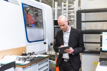 Biznesmen za pomocą tabletu w nowoczesnej fabryce