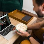 Dzień wolny. Szczęśliwy mężczyzna szukający fajnego filmu w serwisie streamingowym online podczas jedzenia popcornu