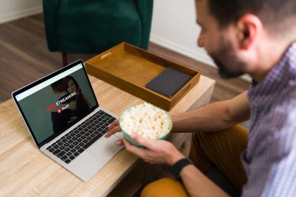 Dzień wolny. Szczęśliwy mężczyzna szukający fajnego filmu w serwisie streamingowym online podczas jedzenia popcornu