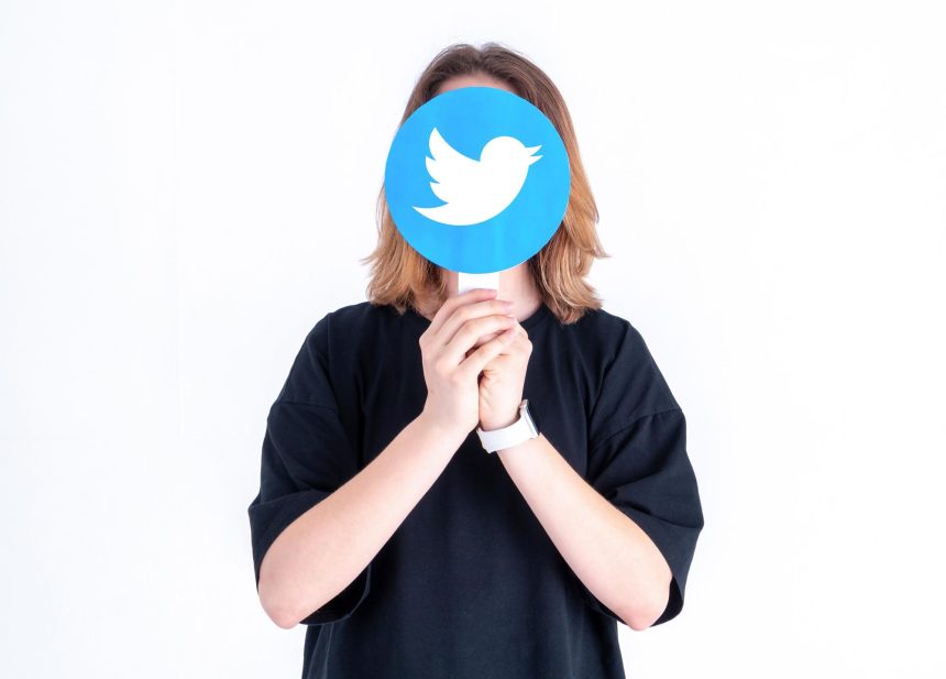 Kaukaski nastolatek trzymający w dłoniach zdjęcie z logo Twittera na białym tle
