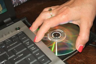 Ręka kobiety biorąca płytę DVD z laptopa