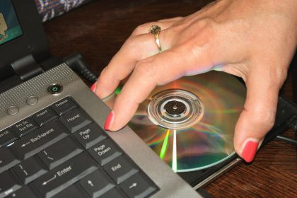 Ręka kobiety biorąca płytę DVD z laptopa