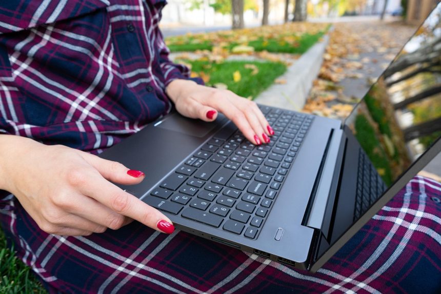 Student studiujący na zewnątrz Zbliżenie nowoczesnej dziewczyny siedzącej na trawie pod laptopem w parku Ręce na klawiaturze