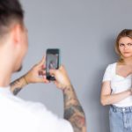 Uśmiechnięta para używająca telefonów w studio Izolowane ciemne tło