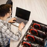 Widok z góry programisty pracującego nad swoją platformą do wydobywania kryptowalut, sprawdzającą wartość bitcoinów i zarobki