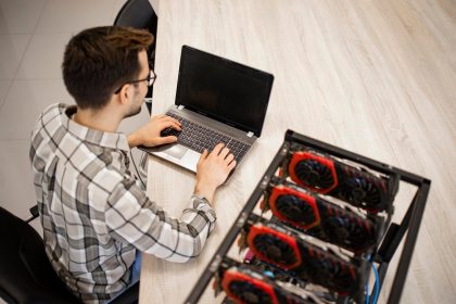Widok z góry programisty pracującego nad swoją platformą do wydobywania kryptowalut, sprawdzającą wartość bitcoinów i zarobki