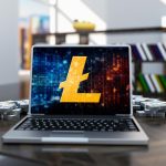 Złota moneta litecoin w laptopie na tle pokoju biurowego