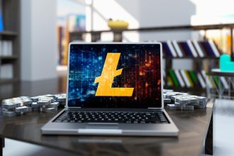 Złota moneta litecoin w laptopie na tle pokoju biurowego