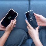 Dwie nastolatki z telefonami w rękach siedzą w domu na łóżku. Tiktok mediów społecznościowych jest ładowany na ekranie.