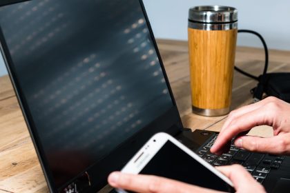 Kobieta korzystająca z telefonu komórkowego w biurze z laptopem i kawą