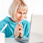 Kobieta biznesu słucha wykładu edukacyjnego na komputerze, oglądając webinarium, studiując na kursach online, pisząc notatki w koncepcji e-learningowej zeszytu papierowego