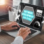 Koncepcja cyklu życia rozwoju oprogramowania Biznesmen używający laptopa na biurku z ikoną cyklu życia opracowania oprogramowania na wirtualnym ekranie