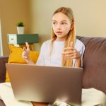 Mała dziewczynka z długimi włosami za pomocą laptopaodrabiania lekcji w domuPowrót do koncepcji szkoły
