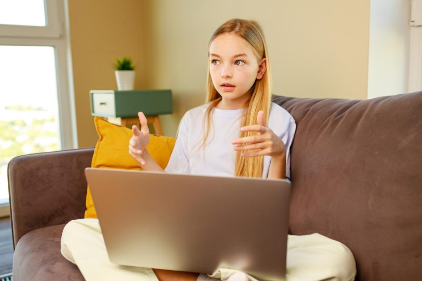 Mała dziewczynka z długimi włosami za pomocą laptopaodrabiania lekcji w domuPowrót do koncepcji szkoły