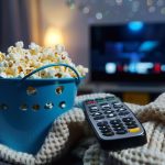 Wiadro z popcornem z zdalnym sterowaniem telewizorem na miły wieczorny film lub serię MacroAI Generative