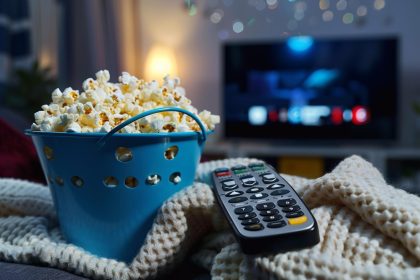 Wiadro z popcornem z zdalnym sterowaniem telewizorem na miły wieczorny film lub serię MacroAI Generative