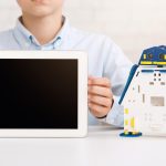 Chłopiec trzymający tablet przed zabawką robotyczną
