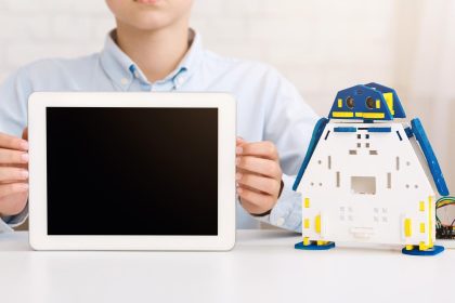 Chłopiec trzymający tablet przed zabawką robotyczną