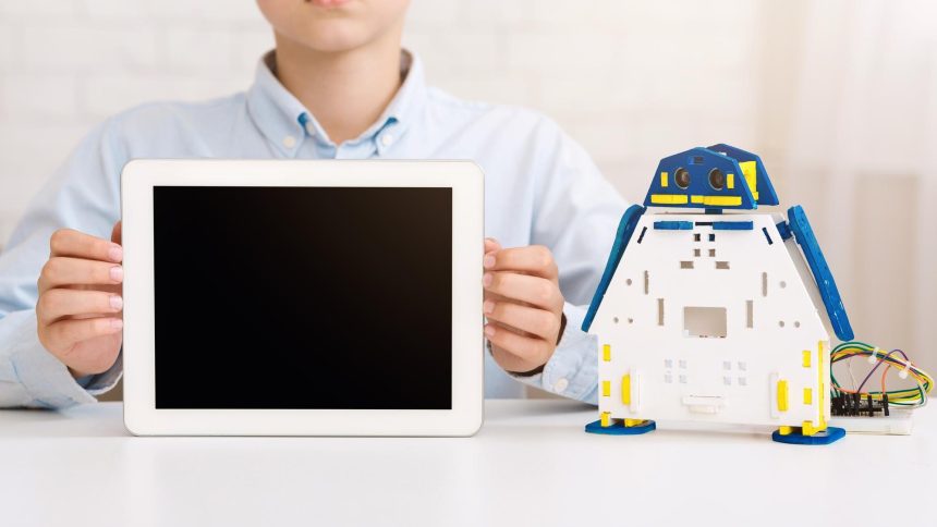 Chłopiec trzymający tablet przed zabawką robotyczną