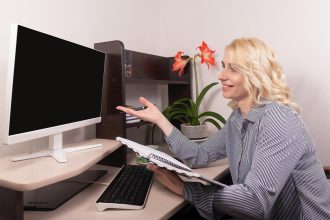 Uśmiechnięta kobieta siedzi przy biurku Praca w domu