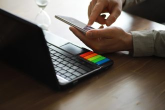 Ręce używające laptopa i telefonu do zakupów online zbliżą czysty obraz przed oknem w miękkim świetle