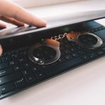 Metalowe kajdanki na czarnej klawiaturzeKajdanki na laptopie zbliżenie Koncepcja cyberprzestępczości hakerskiej