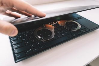 Metalowe kajdanki na czarnej klawiaturzeKajdanki na laptopie zbliżenie Koncepcja cyberprzestępczości hakerskiej