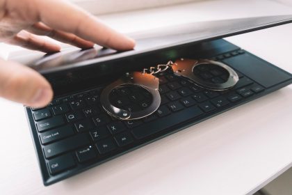 Metalowe kajdanki na czarnej klawiaturzeKajdanki na laptopie zbliżenie Koncepcja cyberprzestępczości hakerskiej