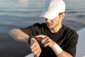 Patrzy na wyniki w aplikacji fitness Watch, sportowiec trenujący w mieście w odzieży sportowej